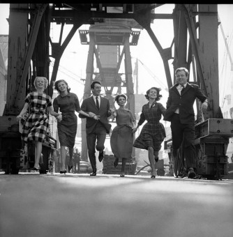 A group of models in autumn/winter outfits at a dockyard by Brian Duffy (1960)