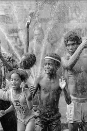 Children cool off under the spray in Brooklyn's Bushwick neighborhood by Allan Tannenbaum (1977)