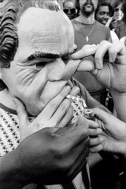 A man in Richard Nixon mask smokes a joint at the Marijuana Smoke-In and March by Allan Tannenbaum (1974)
