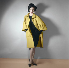 Model wearing bright yellow coat over black dress by Horst P. Horst (1961)
