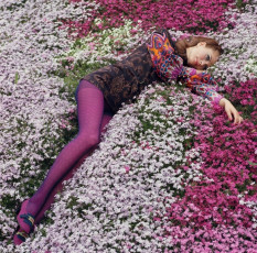 A female fashion model lies in a colourful flower bed by Norman Parkinson (1968)